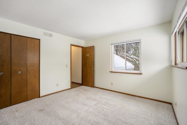 unfurnished bedroom with light carpet, a textured ceiling, and a closet