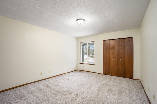 unfurnished bedroom featuring light carpet, a closet, and a textured ceiling