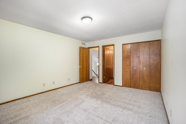 unfurnished bedroom with carpet floors, a textured ceiling, and a closet