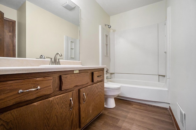 full bathroom featuring hardwood / wood-style flooring, bathing tub / shower combination, vanity, a textured ceiling, and toilet