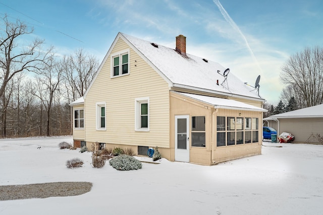 snow covered house featuring a sunroom