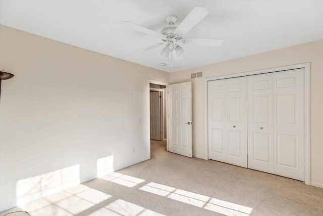 unfurnished bedroom with light colored carpet, ceiling fan, and a closet