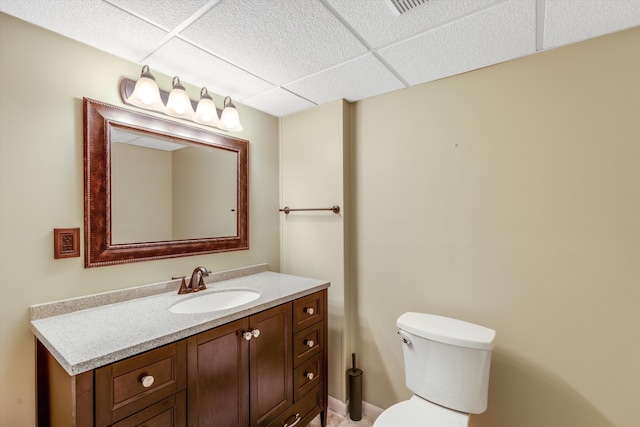 bathroom with vanity, a drop ceiling, and toilet