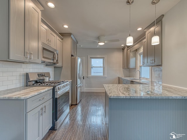 kitchen featuring sink, decorative light fixtures, appliances with stainless steel finishes, dark hardwood / wood-style flooring, and kitchen peninsula