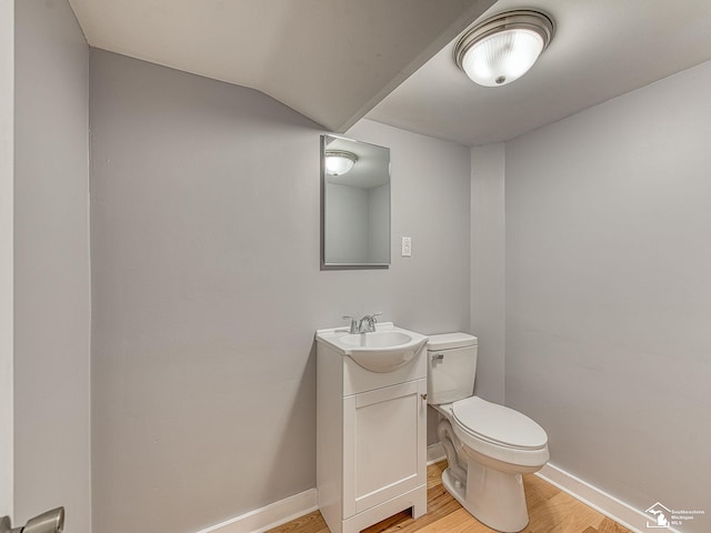 bathroom with lofted ceiling, wood-type flooring, toilet, and vanity