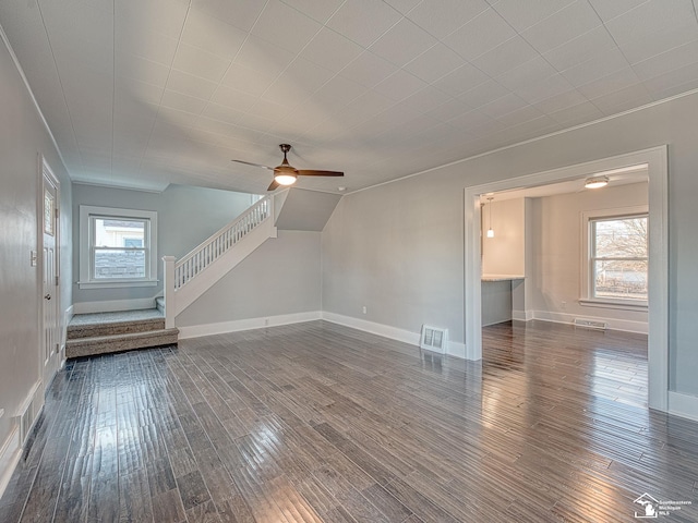 unfurnished living room featuring plenty of natural light, dark hardwood / wood-style floors, and ceiling fan