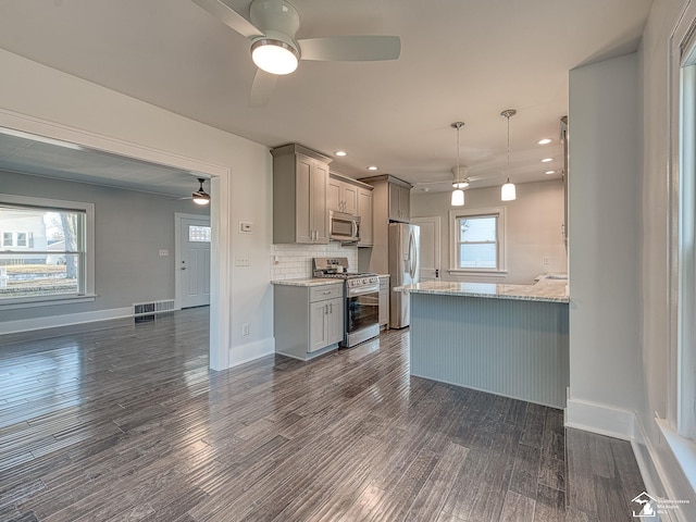 kitchen featuring dark wood-type flooring, appliances with stainless steel finishes, hanging light fixtures, and gray cabinetry