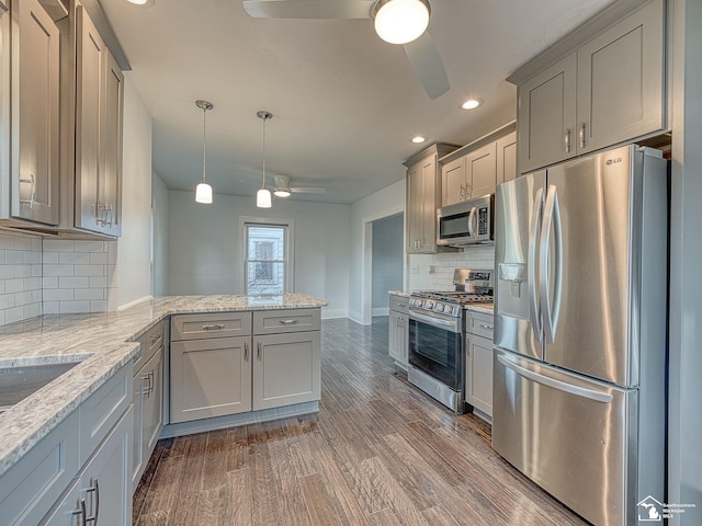 kitchen with hanging light fixtures, ceiling fan, kitchen peninsula, stainless steel appliances, and dark wood-type flooring