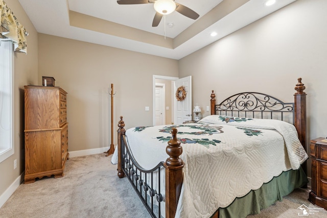 bedroom with light carpet, a raised ceiling, and ceiling fan