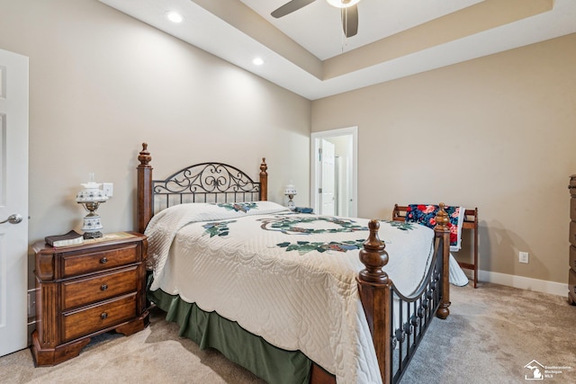 carpeted bedroom featuring ceiling fan and a tray ceiling