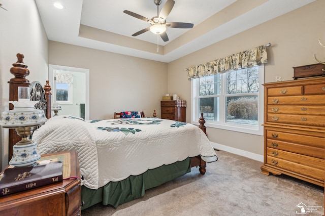 carpeted bedroom with a tray ceiling and ceiling fan