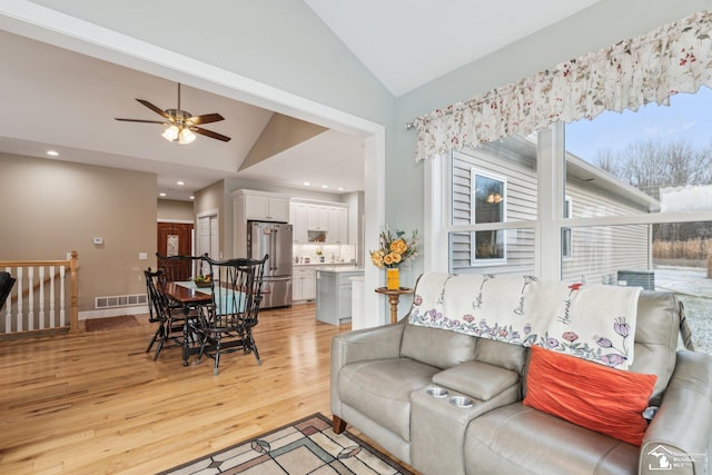 living room featuring ceiling fan, lofted ceiling, and light hardwood / wood-style flooring