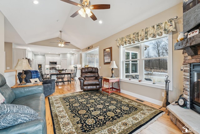 living room with ceiling fan, lofted ceiling, a fireplace, and light hardwood / wood-style flooring