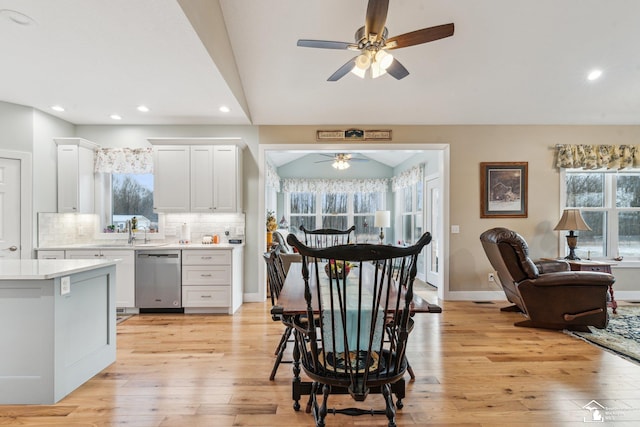 kitchen with white cabinetry, decorative backsplash, stainless steel dishwasher, and light hardwood / wood-style floors