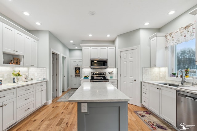 kitchen featuring sink, a kitchen island, white cabinets, and appliances with stainless steel finishes