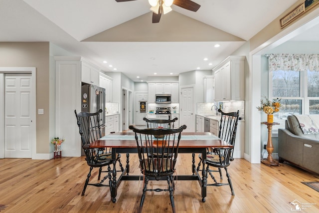 dining space with sink, vaulted ceiling, ceiling fan, and light wood-type flooring