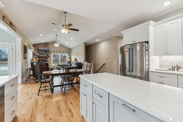 kitchen featuring white cabinetry, lofted ceiling, decorative backsplash, high end fridge, and light wood-type flooring