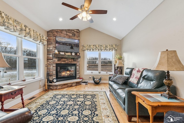 living room featuring vaulted ceiling, ceiling fan, a fireplace, and light hardwood / wood-style floors