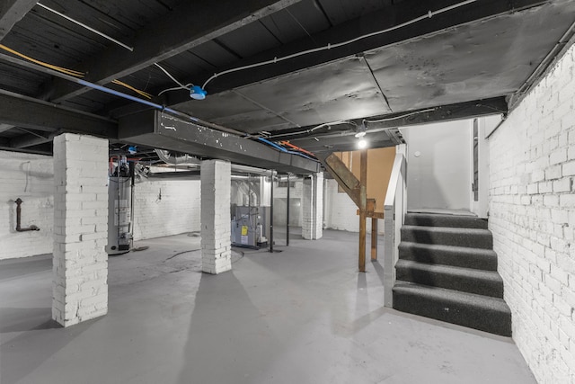 basement with heating unit, water heater, and brick wall