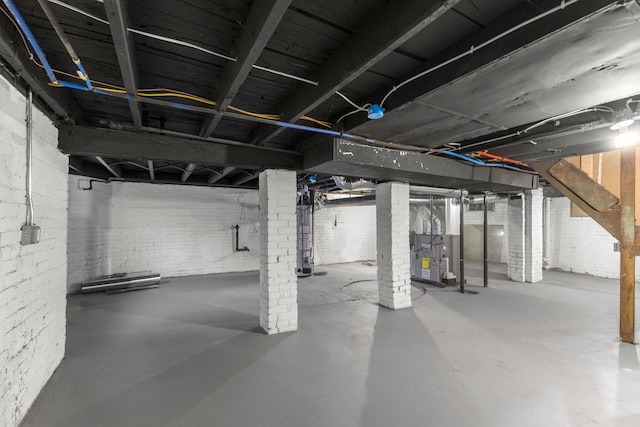 basement featuring water heater, brick wall, and heating unit