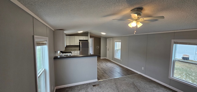 kitchen featuring vaulted ceiling, black fridge, white cabinets, and a textured ceiling