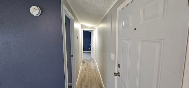 hall featuring a textured ceiling and light hardwood / wood-style floors