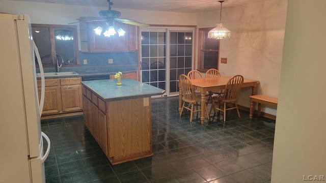 kitchen with pendant lighting, sink, white fridge, a center island, and ceiling fan