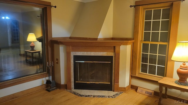 details featuring a tiled fireplace and hardwood / wood-style floors