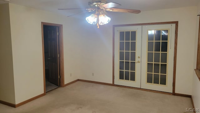 carpeted spare room featuring ceiling fan and french doors