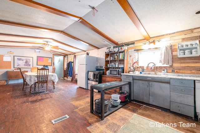 kitchen with lofted ceiling with beams, sink, stainless steel appliances, dark wood-type flooring, and a textured ceiling