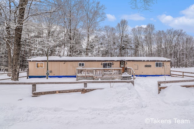 snow covered back of property featuring a wooden deck