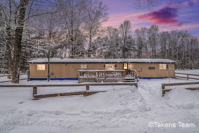 snow covered back of property featuring a deck