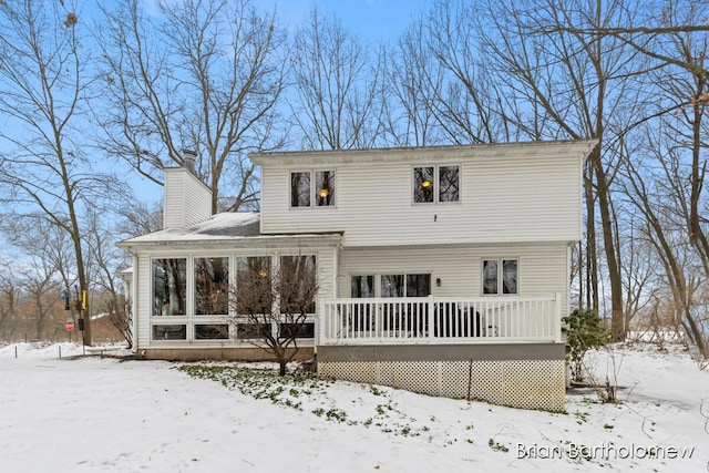 snow covered property with a wooden deck and a sunroom