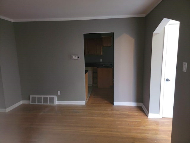 spare room with crown molding and light hardwood / wood-style flooring