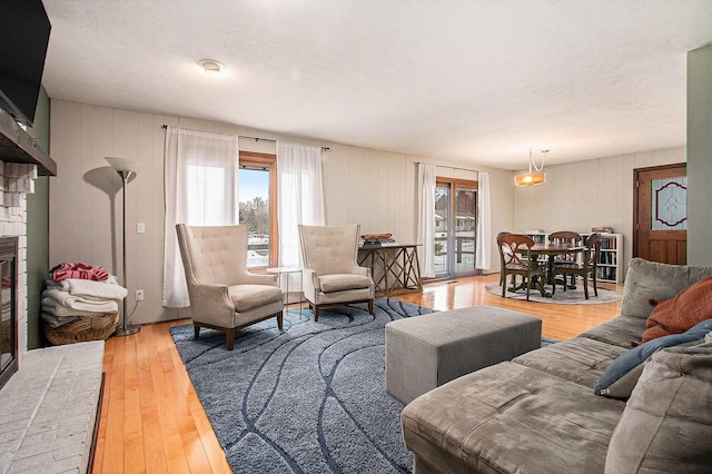 living room with wood-type flooring, a textured ceiling, a fireplace, and a healthy amount of sunlight