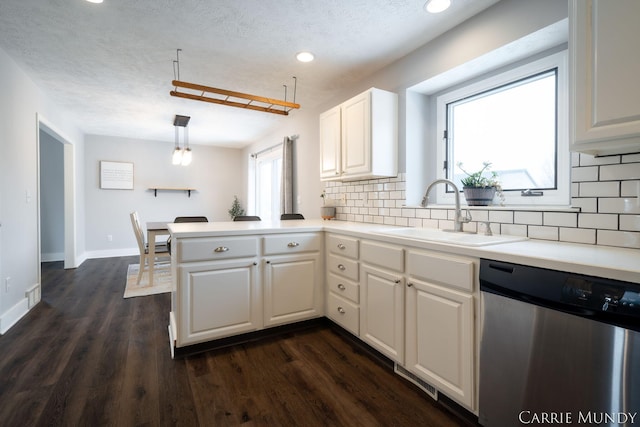 kitchen featuring sink, white cabinetry, decorative light fixtures, stainless steel dishwasher, and kitchen peninsula