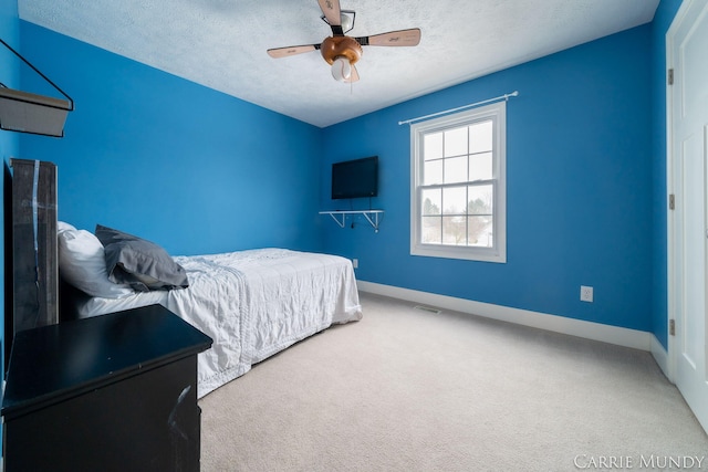 carpeted bedroom featuring ceiling fan and a textured ceiling