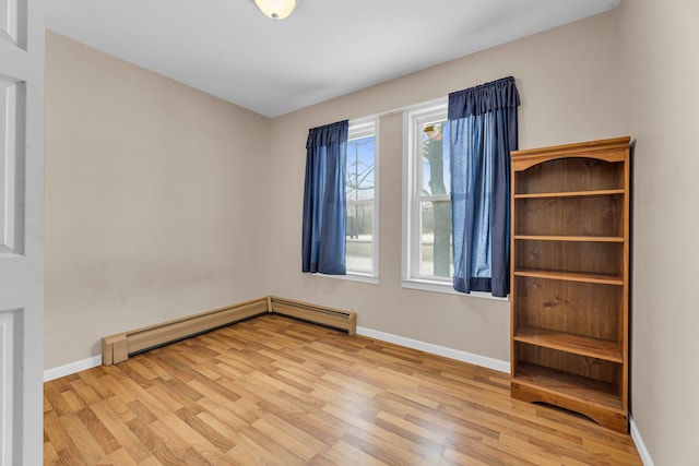 unfurnished bedroom featuring a baseboard heating unit and light hardwood / wood-style floors