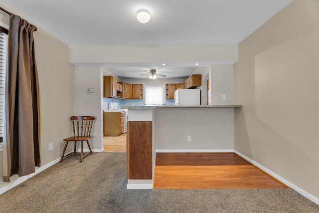 kitchen featuring ceiling fan, carpet, white appliances, and kitchen peninsula