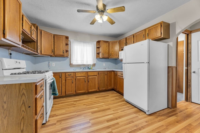 kitchen with sink, white appliances, ceiling fan, light hardwood / wood-style floors, and a textured ceiling