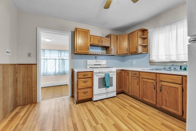 kitchen featuring sink, light wood-type flooring, baseboard heating, ceiling fan, and white gas range oven