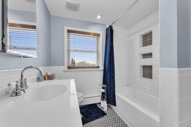 full bathroom with sink, shower / bath combo, tile walls, tile patterned floors, and toilet