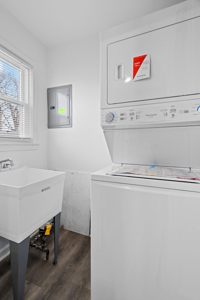 laundry room featuring stacked washer and dryer, electric panel, and dark hardwood / wood-style flooring