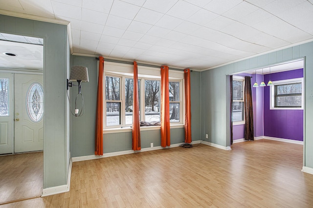 foyer featuring ornamental molding, a healthy amount of sunlight, and light wood-type flooring