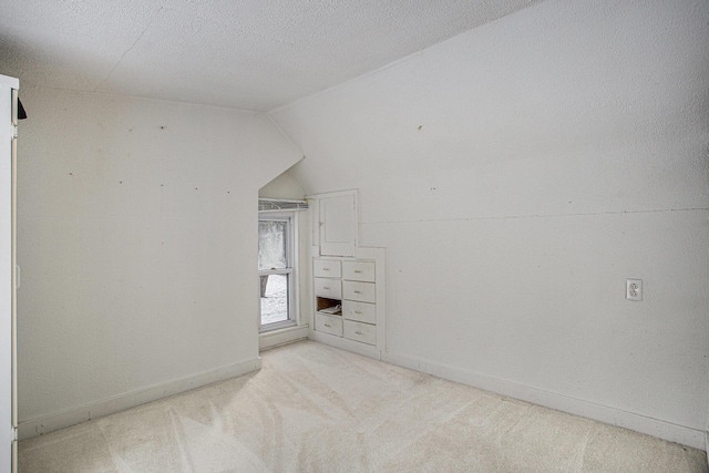 unfurnished room with lofted ceiling, light carpet, and a textured ceiling