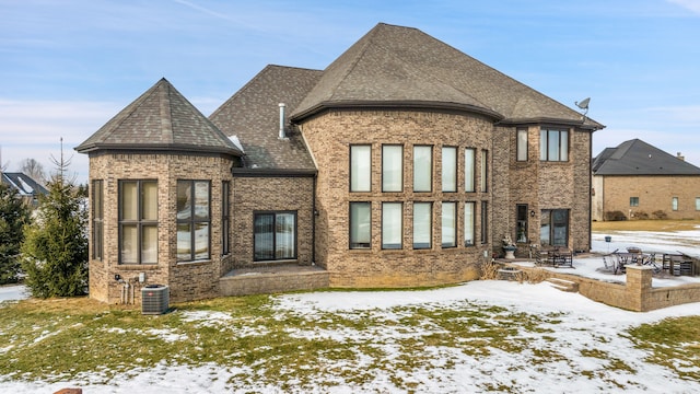 snow covered rear of property featuring central air condition unit