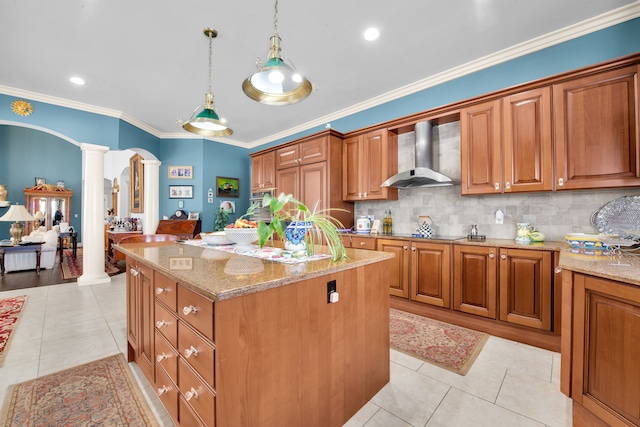 kitchen with wall chimney range hood, light tile patterned floors, decorative columns, and hanging light fixtures