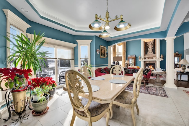 dining room with decorative columns, a healthy amount of sunlight, and a tray ceiling