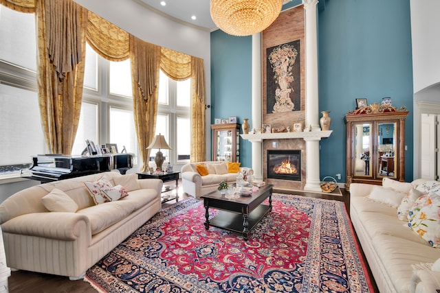 living room with a towering ceiling, a fireplace, hardwood / wood-style flooring, ornamental molding, and an inviting chandelier