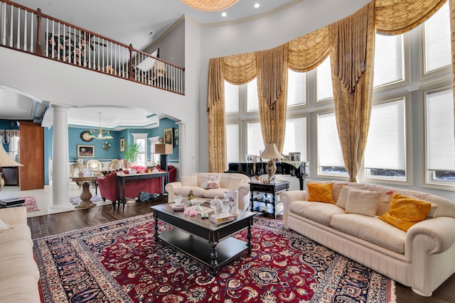 living room with a towering ceiling, ornamental molding, decorative columns, and dark hardwood / wood-style floors